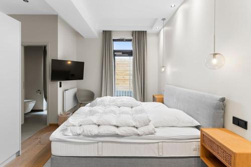 a bedroom with a white bed and a television at Luxus Meerblick Strand & Sauna & Garten & Heimkino in Glowe