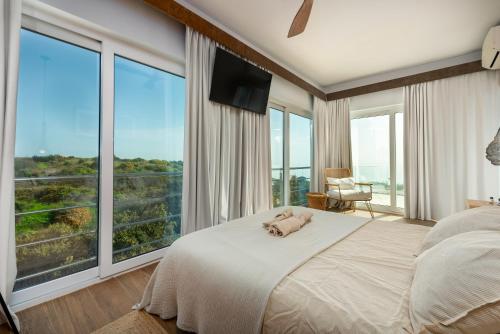 a bedroom with a large bed and large windows at Villa Punta Europa - Private pool with Seaview in Torreguadiaro