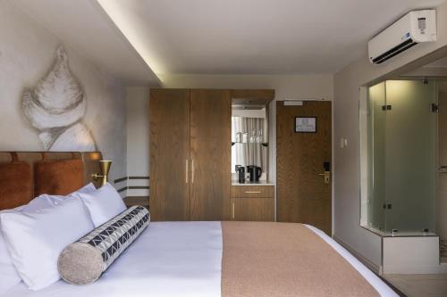 a bedroom with a large white bed and a tv at Mpilo Boutique Hotel in Maseru