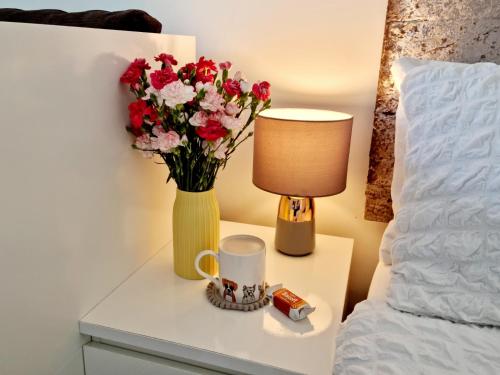 a vase of flowers on a table next to a bed at Wordsworth - Peaceful Place in Bournemouth
