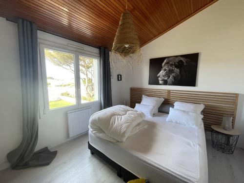 une chambre avec un grand lit blanc avec une fenêtre dans l'établissement L Oiseau, à Saint-Hilaire-de-Riez