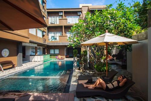 a woman laying on a chair next to a swimming pool at Mazi Design Hotel by Kalima in Patong Beach