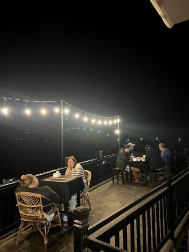 a group of people sitting at tables on a deck at night at Bandipur Good Hotel Inn in Bandīpur
