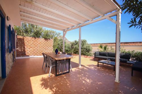 a pergola on a patio with a table and a couch at Dimore di mare - Beachfront Apartments in Santa Flavia