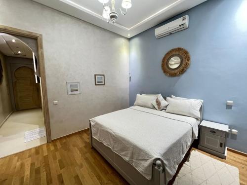 a bedroom with a bed with a blue wall at Splendide Villa 5 chambres de luxe PRIVATISEE avec Cuisinière - Piscine chauffée - Jacuzzi & Hammam in Had Abdallah Rhiat