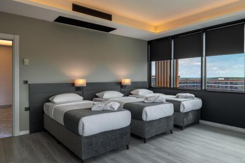 a hotel room with three beds and windows at The Plaza Hotel Edirne in Edirne