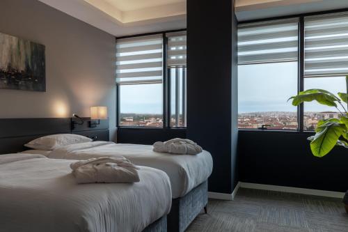 two beds in a room with large windows at The Plaza Hotel Edirne in Edirne