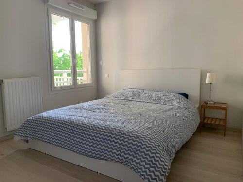 Ce lit se trouve dans une chambre blanche dotée d'une fenêtre. dans l'établissement Appartement Gujan Mestras premier étage, à Gujan-Mestras