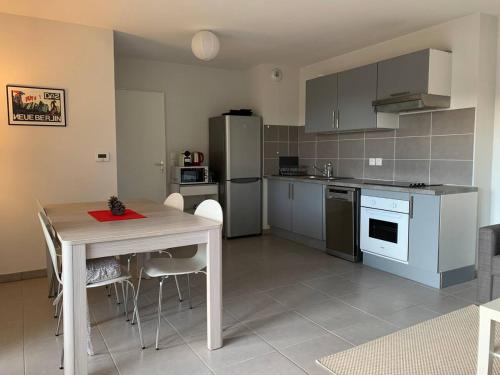 Il comprend une cuisine équipée d'une table, d'une table et d'un réfrigérateur. dans l'établissement Appartement Gujan Mestras premier étage, à Gujan-Mestras