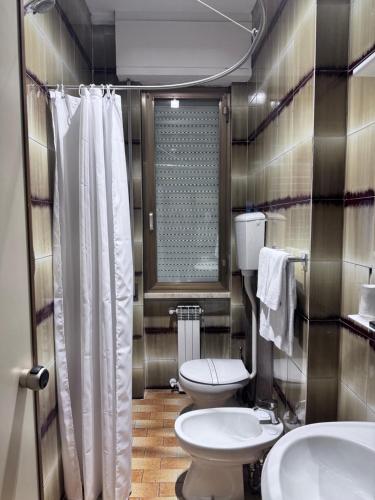 a bathroom with a toilet and two sinks and a shower at Hotel La Magione in Poggibonsi