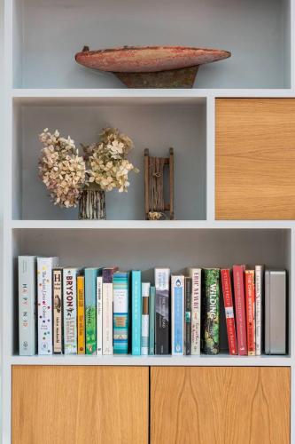 a book shelf filled with books and a vase of flowers at Stylish cottage in Bembridge in Bembridge