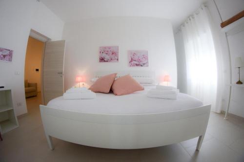 a white bedroom with a white bed with pink pillows at Villa Vera in Salerno