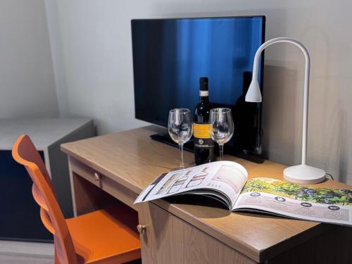a desk with a book and wine glasses and a lamp at Hotel La Magione in Poggibonsi