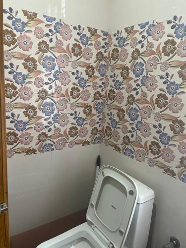 a bathroom with a toilet with a floral wallpaper at Amazing Homestay in Guwahati