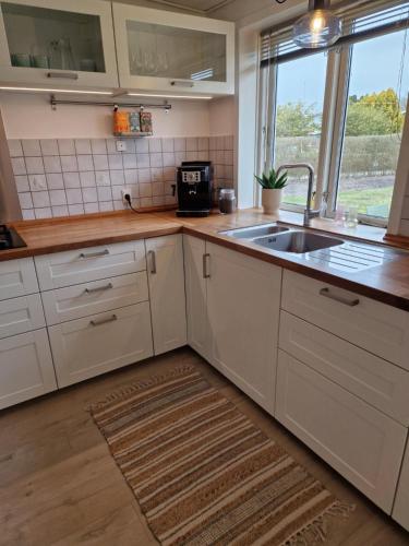 a kitchen with white cabinets and a sink at Rummeligt og stilfuldt hus nær Billund med 4 værelser og egen have in Grindsted