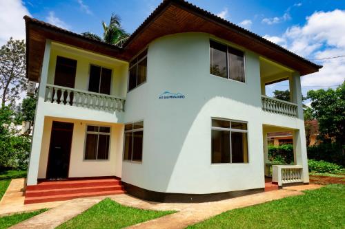 a white house with a brown roof at Keys Hotel Mbokomu Branch in Moshi