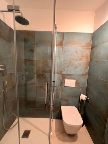a bathroom with a toilet and a glass shower at Le Mimose in Punta Ala