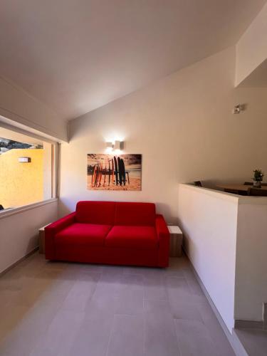 a red couch in a room with a window at Le Mimose in Punta Ala