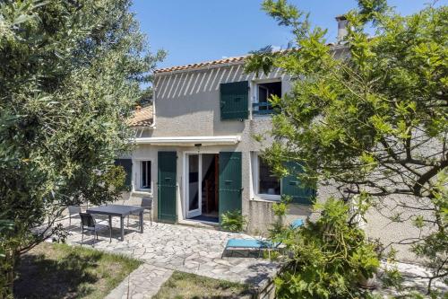 une maison avec une porte verte et une table dans l'établissement Maison 2 pièces avec Mezzanine 6 couchages Dolus D'Oléron DDO000-020, à Dolus-d'Oléron
