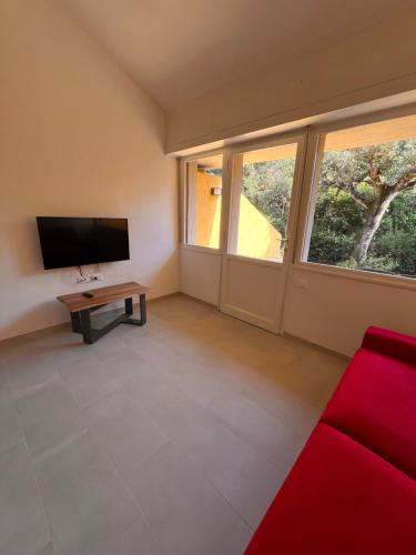 a living room with a red couch and a flat screen tv at Le Mimose in Punta Ala