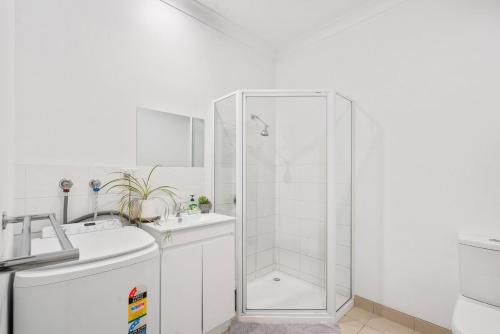 Un baño blanco con ducha y lavabo. en Modern retreat- private entrance - free parking, en Kingston