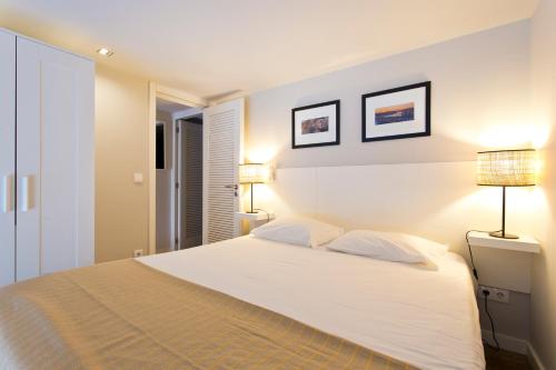 a bedroom with a large white bed with two lamps at RVA - Porto Central Flats in Porto