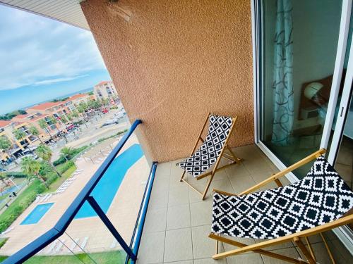 - deux chaises sur un balcon avec vue sur la piscine dans l'établissement Superbe T2 bord de mer belle résidence au port Argeles piscine & parking, à Argelès-sur-Mer