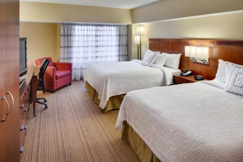 a hotel room with two beds and a red chair at Courtyard Shelton in Shelton