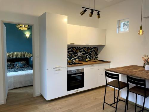 - une cuisine avec des placards blancs, une table et un lit dans l'établissement Agréable maison de ville tout confort Villerurbanne, à Villeurbanne