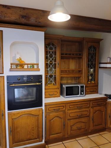 - une cuisine avec des placards en bois et un four micro-ondes dans l'établissement L'A2Milan, maison bourguignonne, à Sainte-Sabine