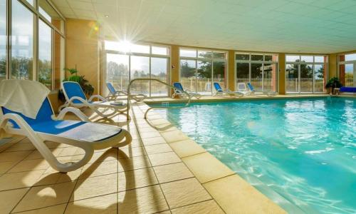 une grande piscine avec des chaises et une table dans l'établissement Vue sur le Golf de Fréhel - Piscine chauffée, à Fréhel