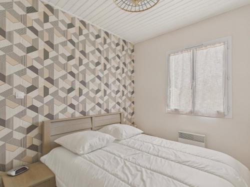 - une chambre dotée d'un lit avec un mur aux accents géométriques dans l'établissement Jolie maison avec extérieur pour 6 proche mer, à Saint-Hilaire-de-Riez