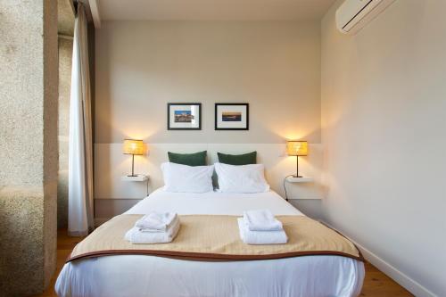 a bedroom with a large white bed with two lamps at RVA - Porto Central Flats in Porto