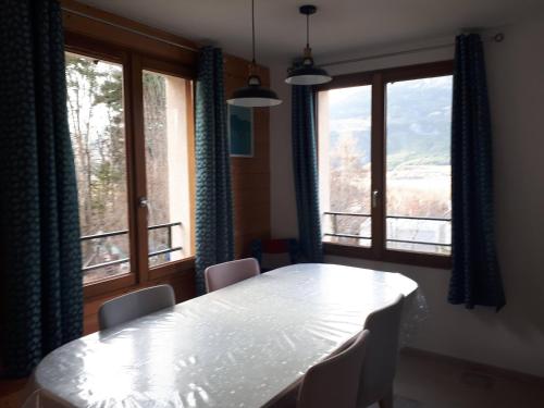 une salle à manger avec une table et deux fenêtres dans l'établissement maison familiale au calme, proche nature, à Crots