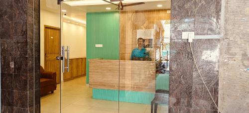 a glass wall in a lobby with a man in a mirror at Akshays Inn in Chengalpattu