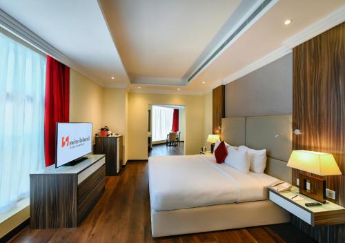 a hotel room with a bed and a flat screen tv at Swiss-Belhotel Seef Bahrain in Manama
