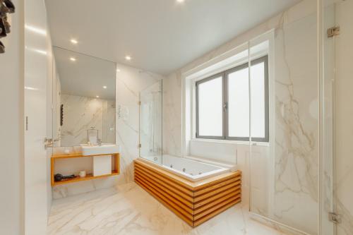 a bathroom with a tub and a sink and a window at Boutique Suites by Hosty in Porto