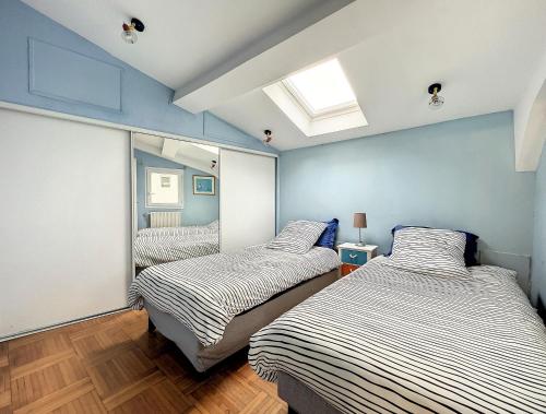 deux lits dans une chambre aux murs bleus dans l'établissement Entre Ciel et Mer, à Sète