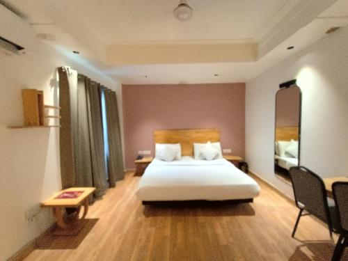 ニューデリーにあるHotel The Centrum New Friends Colonyのベッドとテーブルと椅子のある寝室