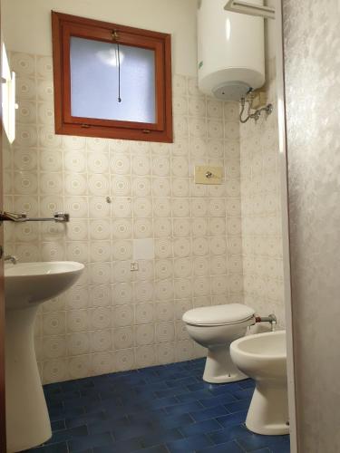 a bathroom with a toilet and a sink and a window at Mughetto in Bibione