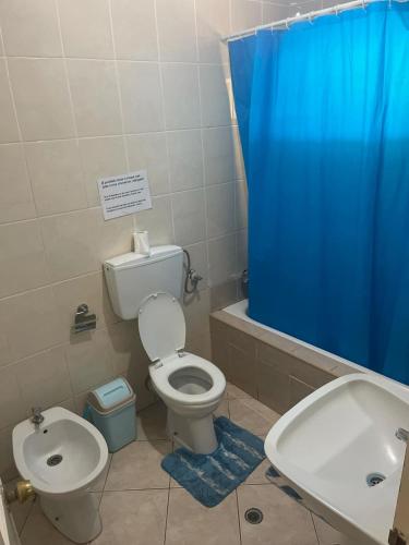 a bathroom with a toilet and a blue shower curtain at Pensão Domingas in São Filipe
