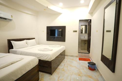 a small room with two beds and a television at Hotel Blissful in Thane