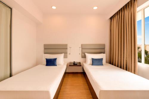 two beds in a room with a window at Keys Select by Lemon Tree Hotels, Hosur Road, Bengaluru in Bengaluru