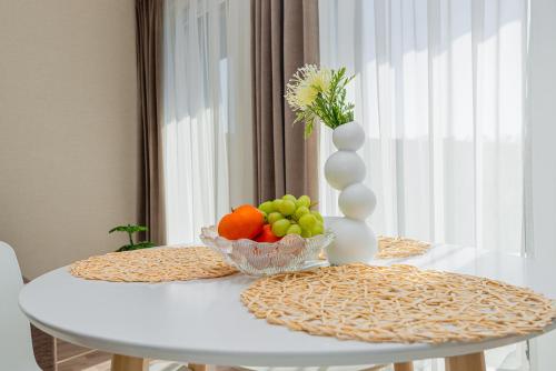 a white table with a bowl of fruit and a vase at Vila Dia Palanga in Palanga