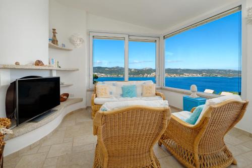 a living room with a tv and wicker chairs at Villa Paradiso in Cala Bitta