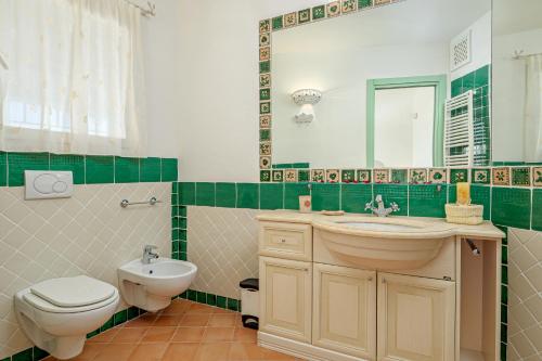 a bathroom with a sink and a toilet and a mirror at Villa Paradiso in Cala Bitta