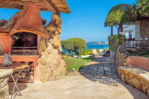 a stone patio with an outdoor oven in front of a house at Villa Paradiso in Cala Bitta