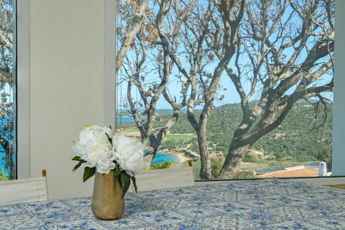 a vase with white flowers on a table with a window at Villa Paradiso in Cala Bitta