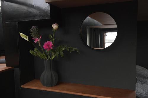 a vase with flowers on a shelf with a mirror at EUPHRATE HOUSeBOAT in Amsterdam