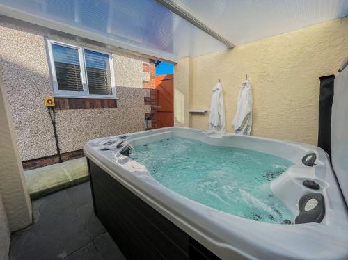 a bathroom with a large bath tub with blue water at Pwyll Holiday Cottage in Pentraeth